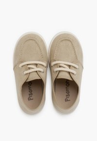 Scarpe in tela beige con suole in gomma, punta rotonda e design allacciato, dotate di lacci intrecciati e un interno liscio con il nome del marchio stampato.