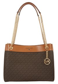 Sac à main marron Michael Kors avec bordure en cuir beige, anses chaînes dorées et breloque logo MK suspendue sur le côté.