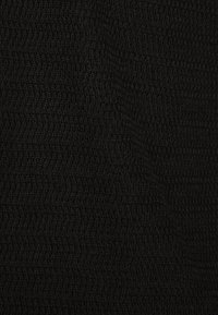 Schwarzer Strickstoff mit einem strukturierten, welligen Muster. Das Material wirkt weich und dicht, geeignet für Bekleidung oder Accessoires.