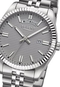 Montre en acier inoxydable argenté avec un cadran gris texturé, des index horaires lumineux, une fonction de date et une lunette rainurée. Équipée d'un bracelet en métal.