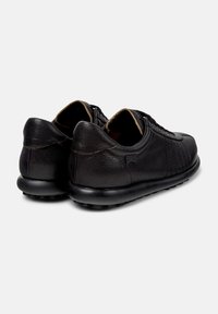 Sneaker in pelle nera con una finitura testurizzata, caratterizzate da un tacco arrotondato e una suola imbottita, esposte da dietro.