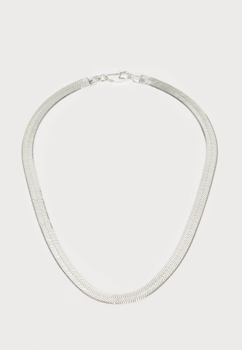 Collar de metal con un diseño de espiga, que presenta un acabado liso en plata, eslabones planos y un cierre seguro. Forma curvada y textura sutil.