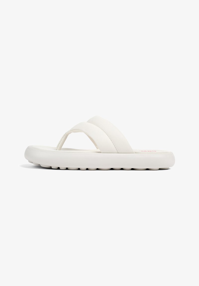 Vit flip-flop med två breda remmar, en platt sula med texturerad botten och ett slätt övre material för komfort och lättbärande.