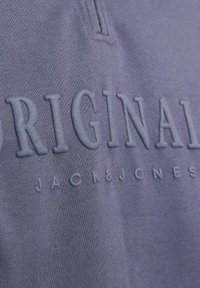 Felpa viola con testo in rilievo "ORIGINAL" e "JACK & JONES" nello stesso colore. Tessuto morbido, design casual, collo alla coreana.
