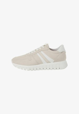 Beige suède sneakers met witte accenten, voorzien van een vetersluiting, geperforeerde neus en een dikke, gestructureerde rubberen zool.