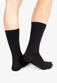 Calze di cotone nere con bordo a costine, lunghezza al polpaccio, texture liscia e design della punta senza cuciture.