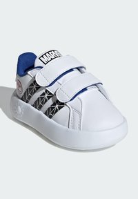 White synthetic shoes with blue accents, featuring two Velcro straps and a black geometric pattern on the side. Rounded toe and rubber sole.