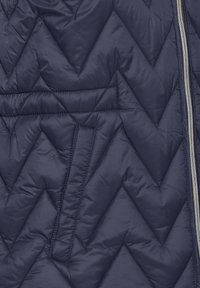 Giacca trapuntata blu navy con motivo a zigzag, chiusura con zip e superficie liscia e lucida. Isolata per garantire calore.