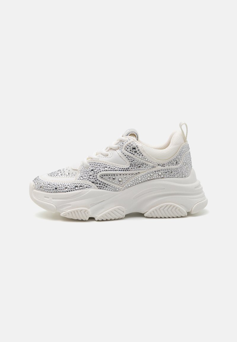 Scarpa sportiva bianca con brillanti strass argento sulla parte superiore, tessuto testurizzato e suola in gomma spessa con un distintivo motivo di battistrada.