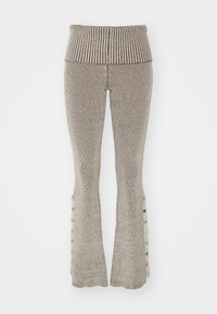 Virknålad utsvängd byxor i beige med vertikal ribbing, en bred midja och knappdetaljer längs den yttre sidan av varje ben.