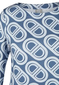 Langarmshirt aus blauer Stoff mit einem sich wiederholenden weißen Kreisdesign. Runder Ausschnitt mit sichtbaren Nähten.