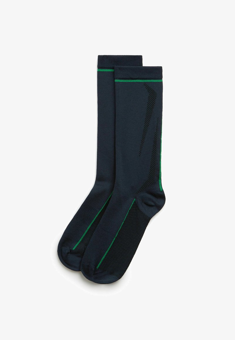 Marine kompressionsstrømper med grønne detaljer, der har et tekstureret panel på siden. Lavet af strækbart materiale for komfort og pasform.
