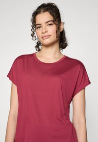 Maroon short-sleeve t-shirt with a round neckline and smooth texture. Subtle logo detail on the front. Relaxed fit and lightweight fabric.