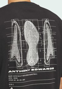 Camiseta negra con un diagrama técnico blanco de suelas de zapatos. Incluye medidas y el nombre "ANTHONY EDWARDS" mostrado prominentemente.