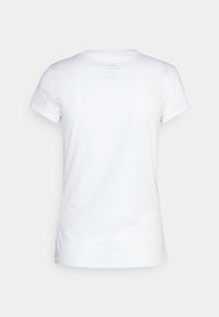 Camiseta de algodón blanca con escote redondo y mangas cortas. Incluye una etiqueta impresa minimalista en la parte superior de la espalda.