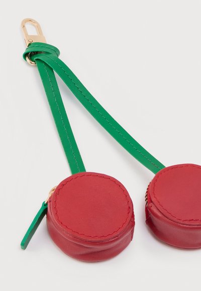 Δερμάτινες κόκκινες θήκες για κέρματα με πράσινο λουράκι και χρυσό εξοπλισμό, με κυκλικά σχήματα και λεπτομερείς ραφές. Ορατό φερμουάρ κλεισίματος.