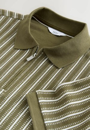Olivgrünes Polohemd mit Reißverschluss vorne, ausgestattet mit vertikalen weißen Streifen und gerippter Textur. Enthält einen Kragen und eine Brusttasche.