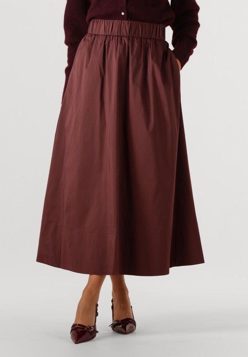 Bruine, knielange A-lijn rok van gladde stof met een elastische tailleband en zijzakken. Gecombineerd met burgundy pumps met spitse neuzen.