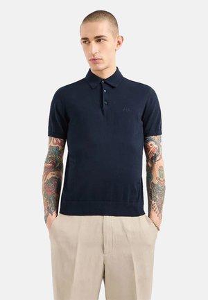 Polo a maniche corte blu navy in tessuto lavorato a maglia, con colletto e logo discreto sul petto.