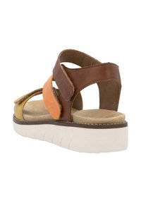 Bruine en oranje leren sandalen met een gevoerd voetbed en een dikke witte zool. Beschikt over kruisbanden en een open achterkant ontwerp.