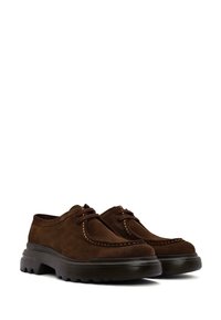Scarpe in suede marrone con punta rotonda, suola in gomma e cuciture a contrasto. Presentano una chiusura con lacci e un design a profilo basso.