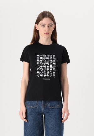 Black cotton t-shirt featuring a graphic of various white facial illustrations. Short sleeves and round neck; casual, relaxed fit.