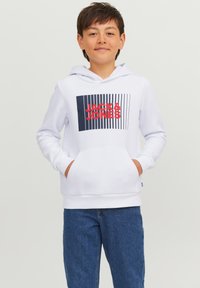 Felpa bianca con cappuccio e tasca frontale, caratterizzata da una stampa grafica rossa e blu con il testo "JACK & JONES". Indossata con jeans blu.