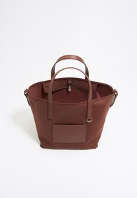 Bolsa tote marrón hecha de material suave, con dos asas resistentes, cierre de cremallera y un bolsillo frontal con detalle de logo en relieve.