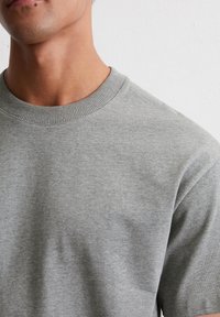 Szary bawełniany sweatshirt z okrągłym dekoltem i krótkimi rękawami, o gładkiej fakturze i prostym wzornictwie.