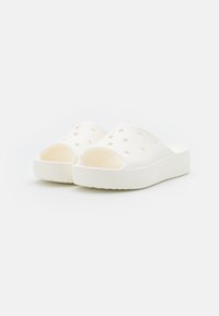 Sandales blanches à enfiler avec plusieurs trous de ventilation, une finition lisse et texturée, et une semelle épaisse et rembourrée.