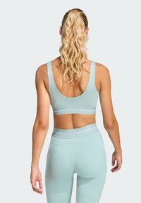 Mint green sports bra and matching leggings, featuring a smooth texture, wide straps, and contrasting elastic bands. Back view shown.