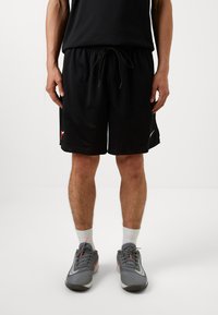 Svarte nettingtrening shorts med elastisk midje og snøring, med logo aksent. Brukt med grå sportsko og hvite sokker.