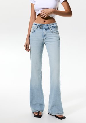 Light blue flared jeans made from cotton denim. Features five-pocket design, belt loops, and a buttoned front closure. Flared bottom style.