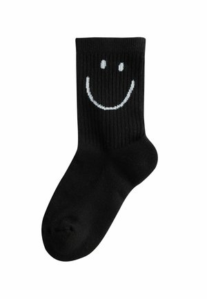 Black crew sock with ribbed texture featuring a white smiley face design on the upper calf area.