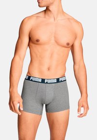 Graue Boxershorts mit einem schwarzen Bund, der das weiße "PUMA"-Logo zeigt. Der Stoff wirkt glatt und elastisch, für Komfort und Passform gestaltet.