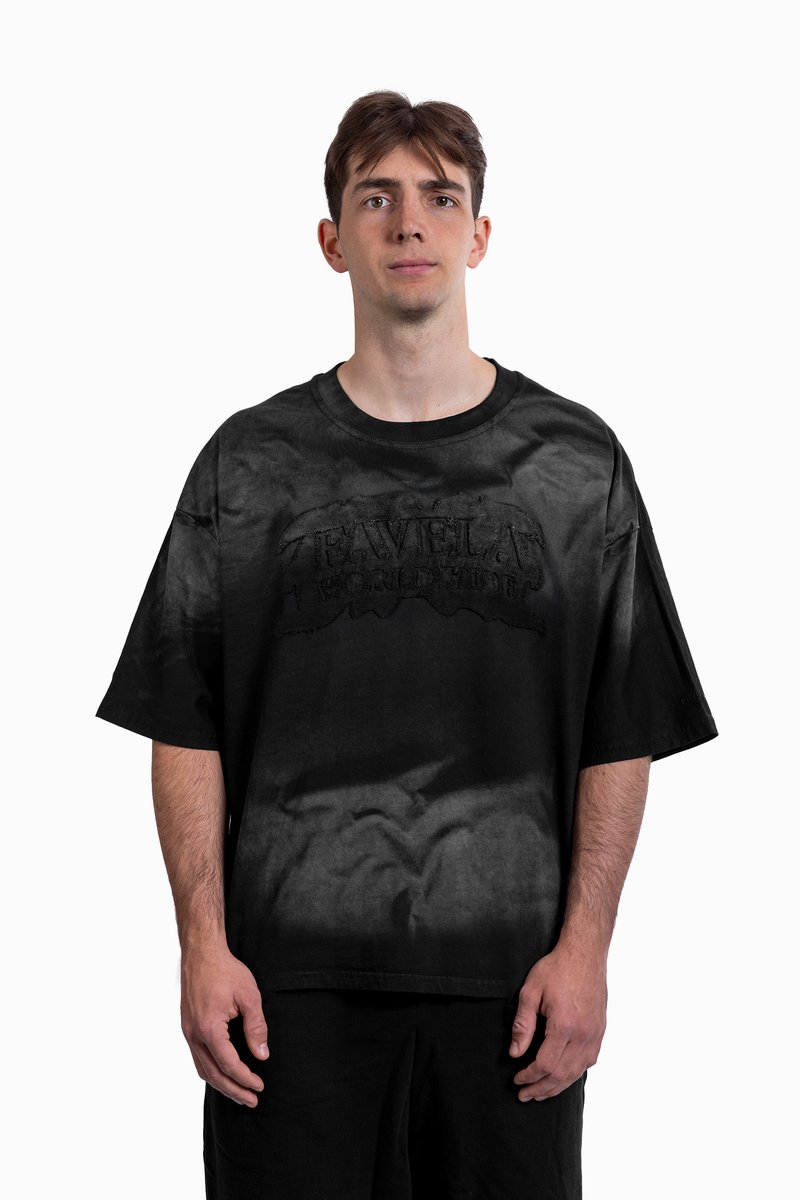 Černé oversize tričko s bledým vzorem a vystouplým logem „FAVELAS WORLDWIDE“ uprostřed. Materiál bavlna, krátké rukávy, kulatý výstřih.