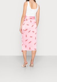 Jupe midi rose en satin, ornée d'un imprimé homard rouge, avec un détail de taille nouée et une fente latérale à l'ourlet.