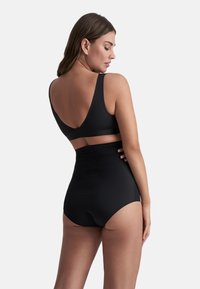 Set bikini nero con top a halter con spalline larghe e slip a vita alta. Texture liscia con design minimalista.