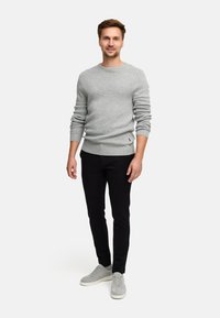 Szary sweter o fakturze z prążkowanymi mankietami, w połączeniu z czarnymi spodniami slim fit i jasnoszarymi sneakersami, minimalne detale brandingowe.