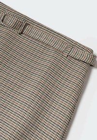 Ceinture en tissu tissé à motif pied-de-poule avec des nuances de brun clair, brun foncé et noir. Comprend un design à boucle à la taille.