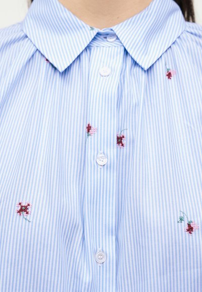 Σιέλ πουκάμισο με ρίγες σε λευκό και ανοιχτό μπλε, με μικρά κεντητά κόκκινα και ροζ λουλούδια, κουμπωμένο μπροστά.