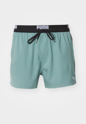 Puma Badehose in hellgrün, mit einem elastischen schwarzen Bund mit Logo, Kordelzug, Seitentaschen und glatter Textur.