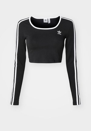 Melnā īsā piedurkne ar garām piedurknēm, kas izgatavota no kokvilnas, ar baltām sānu svītrām un apaļu kakla izgriezumu, ar mazu melnu logotipu uz krūtīm.