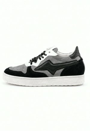 Niskie sneakersy w odcieniach szarości, czerni i bieli z czarnymi sznurowadłami i grubą białą podeszwą na jednolitym tle.