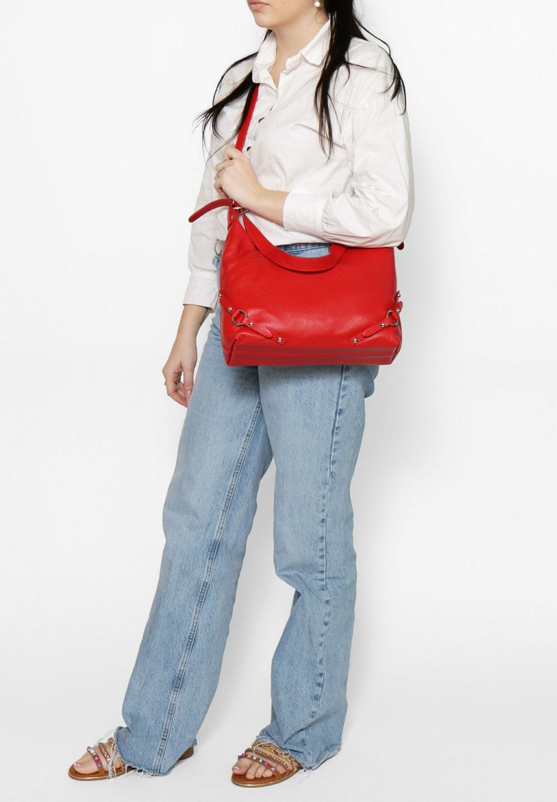 Borsa a mano in pelle rossa con finitura texture, caratterizzata da una silhouette curva, tracolla regolabile e dettagli in metallo.