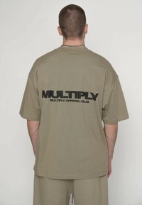 Olivengrøn kortærmet T-shirt med "MULTIPLY" tekst i sort på både for- og bagside. Relaxed pasform og blød tekstur.