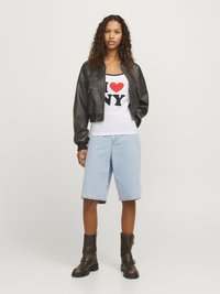 Musta nahkainen pommikauppias takki valkoisen tanktopin päällä, jossa on musta ja punainen "I ♥ NY" -teksti. Vaaleansiniset farkkushortsit ja ruskeat nilkkurit.