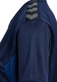 Marinblå sporttröja med mjuk textur. Har en kontrasterande blå panel och en mönstrad svart detalj på axeln.