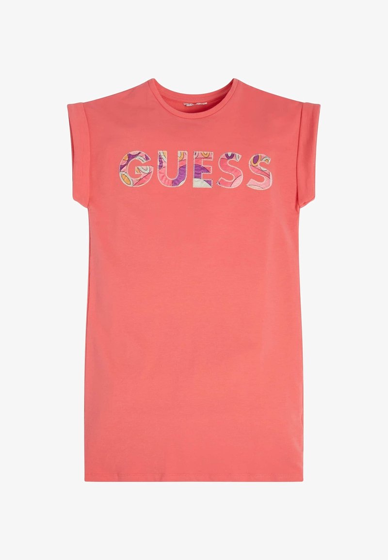 Koralowy bezrękawnik z okrągłym dekoltem. Na froncie widoczny jest napis "GUESS" wykonany kolorowymi literami z wzorem.