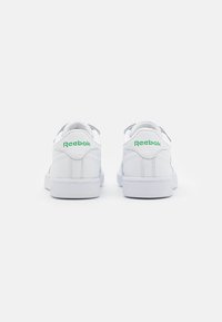 Bijele kožne tenisice s glatkom teksturom, s zelenim Reebok logotipom na peti i klasičnim niskim dizajnom s gumenim potplatom.